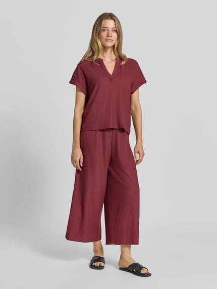 Frauenmodel trägt Regular Fit T-Shirt in Crinkle-Optik von s.Oliver RED LABEL, dunkles Rot, dezente Struktur, Ganzkörperansicht von vorne.