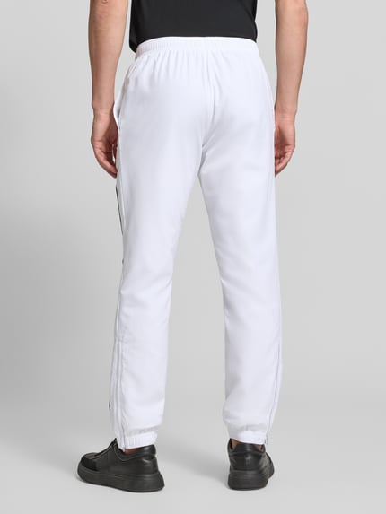 Männermodel trägt weiße Regular Fit Trainingshose mit Logo-Patch von Lacoste, Herren Trainingshose von Lacoste Sport, Ganzkörperansicht Rückansicht.