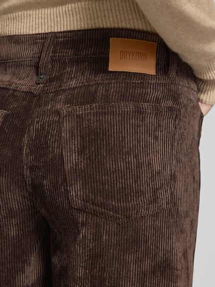 Männermodel trägt Cordhose mit Eingrifftaschen Modell 'MEDLEY' von DRYKORN, szerokość w rozmiarze 27/34: 39 cm, długość nogawki wewnętrznej w rozmiarze 27/34: 83 cm, szerokie nogawki, tkanina sztruksowa, detal tylnej kieszeni, zbliżenie na pośladki.