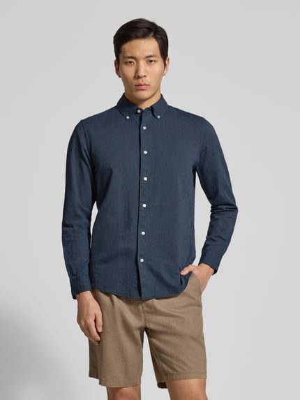 Męski model nosi Slim Fit Freizeithemd aus reiner Baumwolle von MCNEAL, kolor granatowy, długi rękaw, zaokrąglony dół, widok całej sylwetki z przodu.
