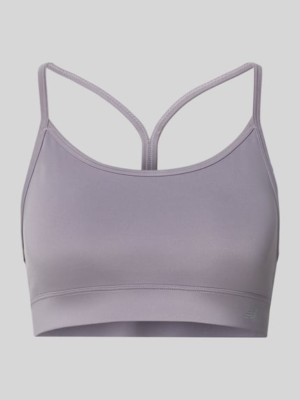 Produktfoto, Yoga BH mit rückseitigem Cut Out von New Balance in Flieder, glatte Oberfläche, Rundhalsausschnitt, Spaghettiträger, Material-Mix mit Stretch-Anteil, herausnehmbare Cups.