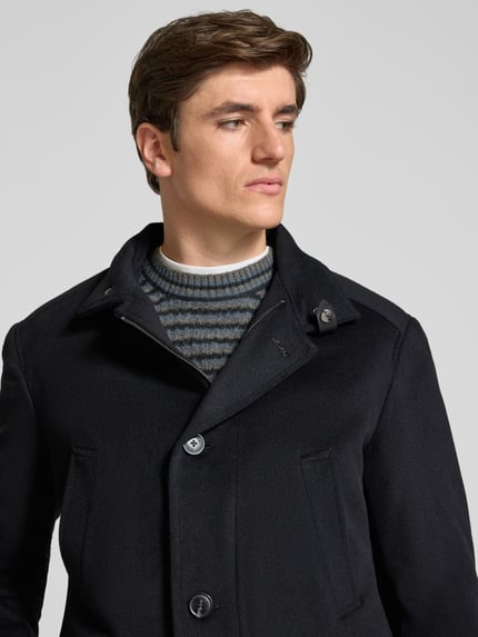 Männermodel trägt Mantel mit Stehkragen Modell '17 JO-48Gary' von JOOP! in Dunkelblau, strukturierte Webware, Nahaufnahme Oberkörper.