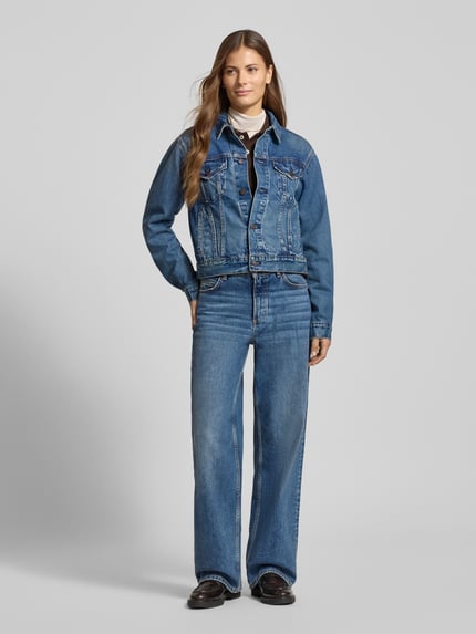 Frauenmodel trägt Regular Fit Jeansjacke aus Baumwoll-Mix von Polo Ralph Lauren in meliertem Blau mit Brusttaschen und Label Patch, Ganzkörperansicht von vorne.