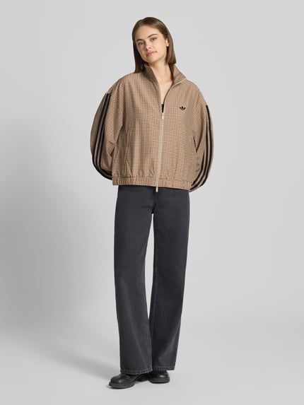 Vrouwenmodel draagt slim fit sweatjack met gestikt logo model 'CHECKS' van adidas Originals in beige met zwart, dames sweatjack, volledige lichaamsaanzicht van voren.