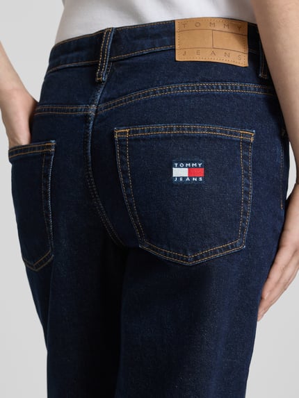 Frauenmodel trägt Straight Fit Jeans aus Baumwoll-Mix Modell 'SOPHIE' von Tommy Jeans in Dark Wash Denim-Optik mit Label-Patch, Label-Prägung, 5-Pocket-Design und Twill-Materialverarbeitung, Nahaufnahme Rückansicht.