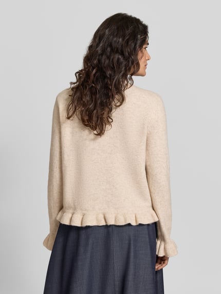Frauenmodel trägt Regular Fit Cardigan mit Rundhalsausschnitt Modell 'Jacia' von VILA, beiger Material-Mix mit Rüschen, Rückansicht, KI-modifiziertes Bild.