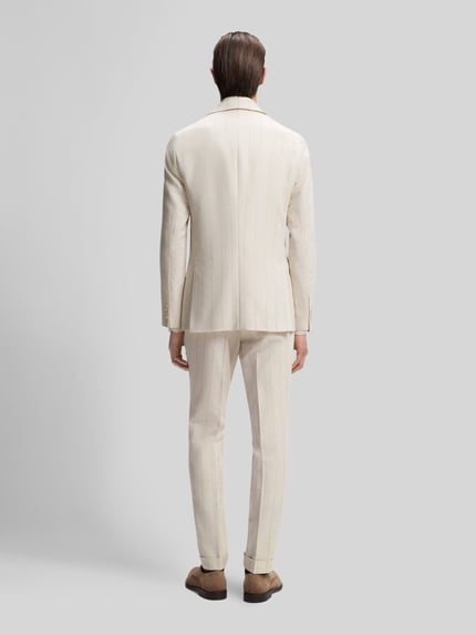 Männermodel trägt Slim Fit Anzug aus Baumwoll-Woll-Mix Modell 'H-HUGE-2PCS-261' von BOSS, efekt: wzór w paski, krój slim fit, marynarka na 2 guziki, szlufki na pasek, kanty, brustasza, kieszenie z patką, kieszeń wewnętrzna, wpuszczane kieszenie, kieszenie z tyłu, mieszanka bawełny i wełny, jasny kolor, gładka faktura, komplet, Ganzkörperansicht Rückansicht