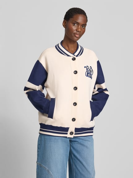 Frauenmodel trägt Relaxed Fit Jacke mit Viskose-Anteil von BAUM & PFERDGARTEN in creme und blau mit Logo-Stitching, Eingrifftaschen, durchgängiger Knopfleiste im Viskose-Baumwoll-Kaschmir-Mix, Brustweite 51 cm, Rückenlänge 72 cm, Ärmellänge 59 cm, Ganzkörperansicht von vorne.