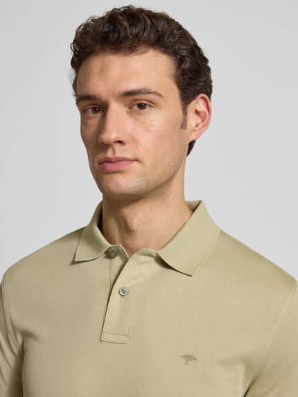 Männermodel trägt Regular Fit Poloshirt mit Logo-Stitching von Fynch-Hatton in Beige, reine Baumwolle, Nahaufnahme Oberkörper.