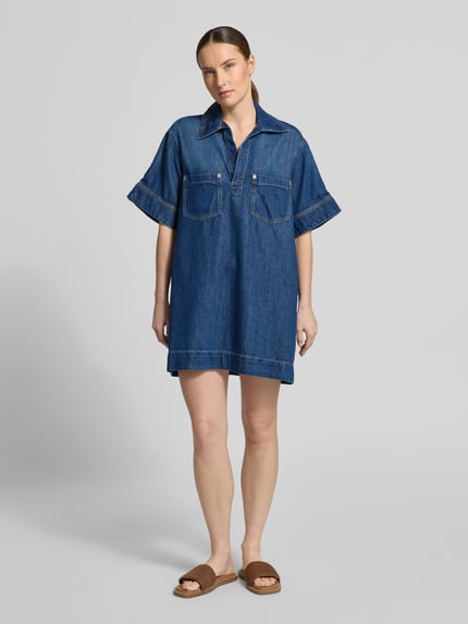 Kobiece modelka nosi Regular-Fit Jeanskleid aus Baumwoll-Mix mit Lyocell-Anteil od BOSS Orange, tkanina stylizowana na denim, krój regular fit, długość mini, dekolt: kołnierz johnny, rękaw: krótki, brustasza, wykończenie materiału: splot twill, mieszanka bawełny i lyocellu, całkowity widok z przodu