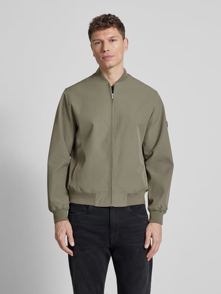 Männermodel trägt heren bomberjack van Jack & Jones Premium in kaki, materiaalmix met stretch, los model, opstaande kraag, ritssluiting, zij-steekzakken, elastische boorden, model 'BLAASPEN', premium kwaliteit, simpele structuur, glad oppervlak. Ganzkörperansicht van voren.