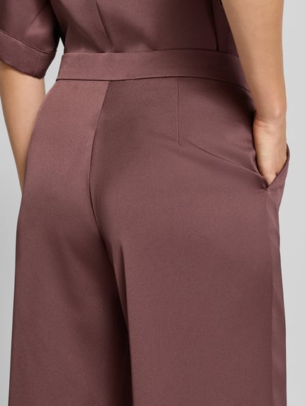 Frauenmodel trägt Straight Fit Hose aus Satin von SWING in Braun, glatte Textur, Detailaufnahme Rückansicht, Kontext: Damen Hose, Satin, Hakenverschluss, Reißverschluss, Bundweite 38 cm, Innenbeinlänge 83 cm bei Größe 36.