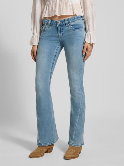 Vrouwenmodel draagt Low Rise Flared Jeans met steekzakken model 'JOEY' van TRUE RELIGION, lichtblauwe denim, flared cut, used-look, volledige lichaamsweergave van voren, katoenmix met stretch.