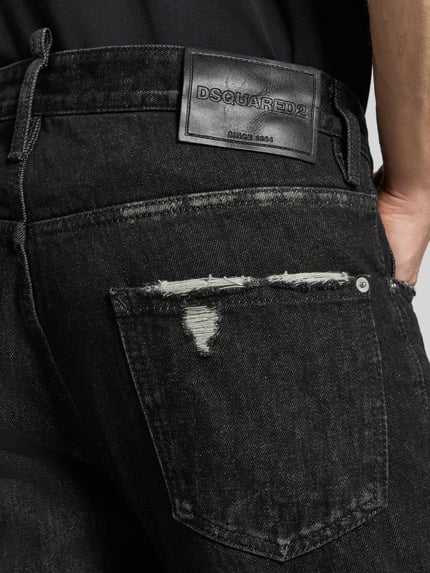 Męski model nosi Straight Fit Jeans aus Baumwoll-Mix Modell 'Teddy' von Dsquared2, Przetarcia, czarny, mieszanka bawełny i elastanu, 5 kieszeni, widok z tyłu, detal. Szerokość w rozmiarze 50: 46 cm, długość wewnętrzna nogawki w rozmiarze 50: 83 cm, zapięcie na guzik i zamek błyskawiczny.