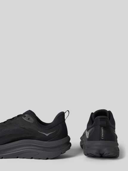 Produktfoto, sneakersy z zaokrąglonym czubkiem, wiązanie, model 'KAWANA 3' od HOKA, detale z logo, wysokość obcasa 4 cm, wysokość cholewki 7 cm, szerokość w rozmiarze 44: 9 cm, czarna kolorystyka, widoczne tekstury meshu i gumowej podeszwy