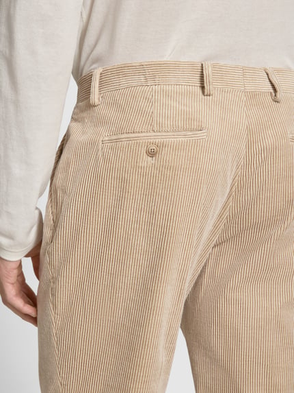 Männermodel trägt Cordhose mit Gesäßtaschen von MCNEAL in Beige mit feiner Rippenstruktur aus Baumwoll-Elasthan-Mix, Detailaufnahme.