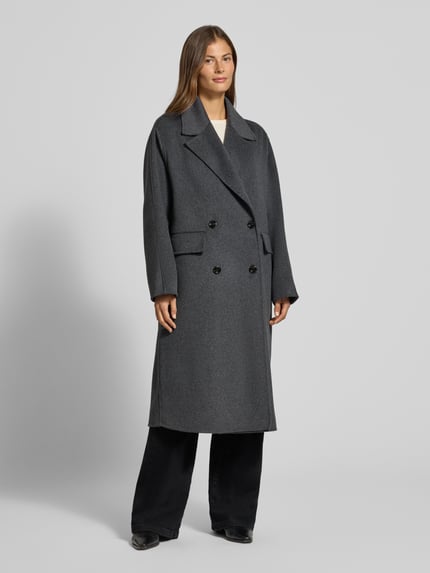 Frauenmodel trägt Regular Fit Mantel aus Woll-Mix mit Baumwoll-Anteil von MANGO in Dunkelgrau mit Reverskragen, Ganzkörperansicht von vorne.