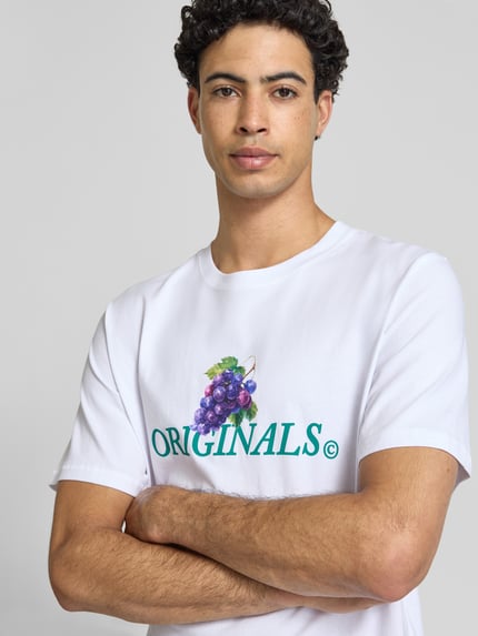 Männermodel trägt Regular Fit T-Shirt mit Statement-Print Modell 'Eres' von Jack & Jones aus reiner Baumwolle, Nahaufnahme Oberkörper.