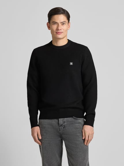 Mannelijk model draagt Regular Fit Strickpullover met scheerwol van HUGO, unie, label patch, ronde hals, lange mouw, voorkant volledig zichtbaar.