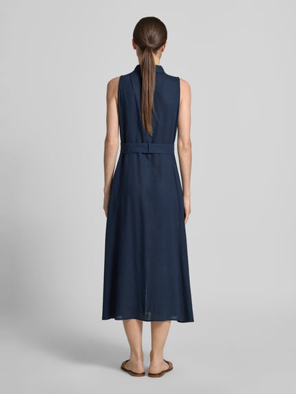 Modelka nosi długa sukienka z mieszanki wiskozy z paskiem 'Maxikleid aus Viskose-Mix mit Gürtel' od Apricot, kolor granatowy, taliowany fason, kołnierzyk koszulowy, listwa guzikowa, mieszanka lnu i wiskozy, długość tyłu w rozmiarze S: 120 cm, szerokość w rozmiarze S: 31 cm, widok całej sylwetki z tyłu.