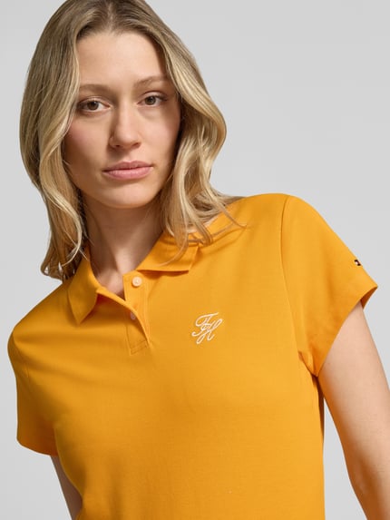 Frauenmodel trägt Slim Fit Poloshirt aus Baumwoll-Mix von Tommy Hilfiger in Unifarben Gelb, kurzer Ärmel, Logo-Stitching auf Brust, Nahaufnahme Oberkörper.