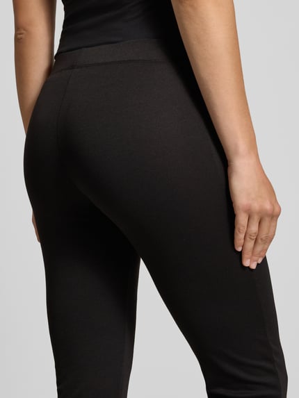 Frauenmodel trägt Slim Fit Schmale Hose mit elastischem Bund Modell 'FEVER' von ONLY in Schwarz, Damen Schmale Hose von ONLY, Nahaufnahme Rückansicht.