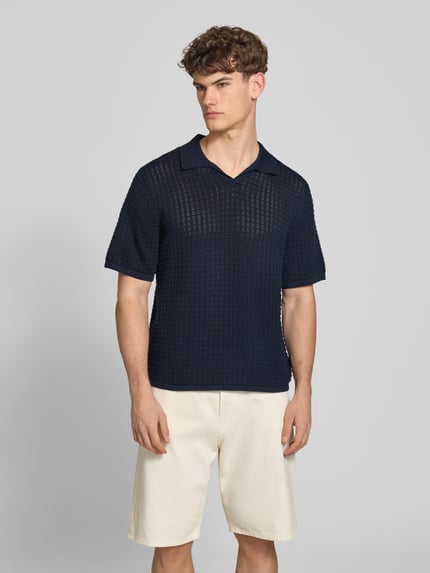 Männermodel trägt Regular Fit Poloshirt mit V-Ausschnitt von Jack & Jones aus reiner Baumwolle als Strickshirt, marineblau, Ganzkörperansicht von vorne.