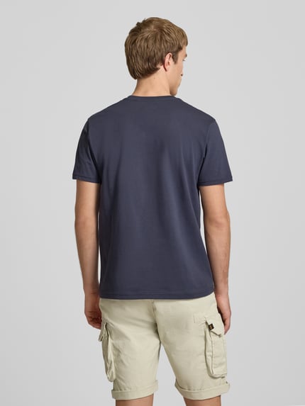 Männermodel trägt T-Shirt mit Logo und Rundhalsausschnitt von Alpha Industries aus Reine Baumwolle, Regular-Fit, Rückenlänge 67 cm, Ganzkörperansicht Rückansicht.