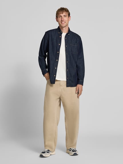 Männermodel trägt Regular Fit Jeanshemd mit Brusttasche Modell 'BROOK' von JACK & JONES, dunkelblau, Baumwolle, Ganzkörperansicht von vorne.