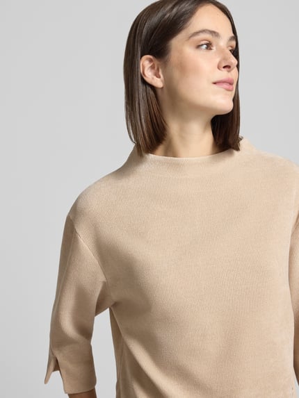 Frauenmodel trägt Relaxed Fit Strickpullover mit Stehkragen von ZABAIONE in Beige, Strick-Optik, 3/4-Arm, Nahaufnahme Oberkörper.