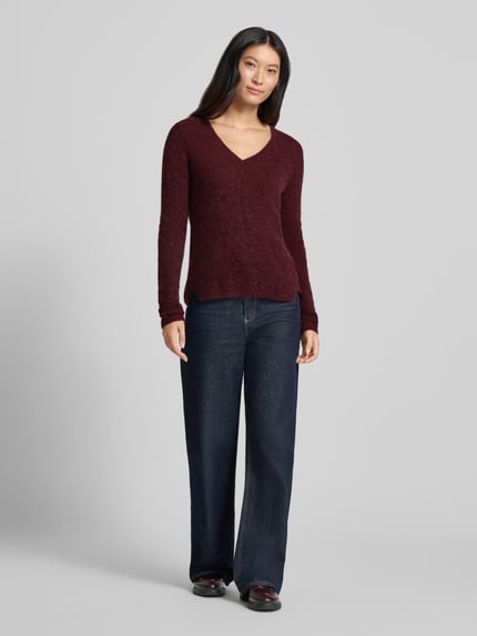 Frauenmodel trägt Slim Fit Strickpullover aus Material-Mix mit Woll-Anteil von MOS MOSH in Bordeaux mit V-Ausschnitt, elastische Abschlüsse, kombiniert mit Jeans, Ganzkörperansicht von vorne.