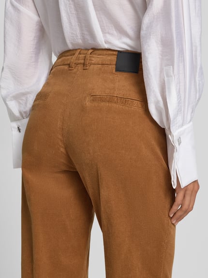 Frauenmodel trägt Cordhose mit aufgeschlagenem Saum von Marc Cain, Baumwoll-Mix, Slim Fit, Struktur durch Feinripp, Nahaufnahme Rückansicht.