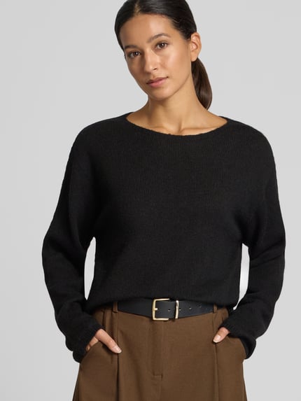 Frauenmodel trägt Strickpullover aus Woll-Mix mit Alpaka-Anteil Modell 'IMENY' von DRYKORN in Schwarz, Oversized Fit, Nahaufnahme Oberkörper.