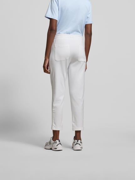 Vrouwenmodel draagt Sweatpants aus Baumwoll-Mix van Juvia in wit, smal toelopende pijpen, elastische taille met trekkoord, steekzakken, elastische boorden, katoen-modal mix, damesmodel, volledige lichaamsweergave achteraan.