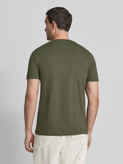 Männermodel trägt Regular Fit T-Shirt aus reiner Baumwolle von s.Oliver RED LABEL in Olivgrün, glatte Textur, Ganzkörperansicht Rückansicht.