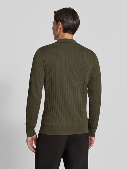 Męski model nosi koszulkę polo o kroju regular fit z czystej bawełny model 'TORINO' od Selected, zielona, czarne spodnie, widok całej sylwetki od tyłu.