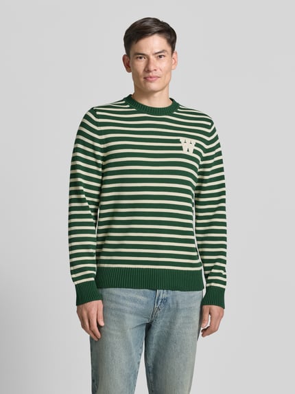 Männermodel trägt Strickpullover mit Rundhalsausschnitt von Wood Wood aus Reine Baumwolle, Gerader-Schnitt, Label-Stitching, Ganzkörperansicht von vorne
