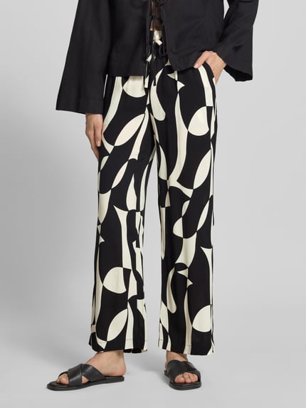 Frauenmodel trägt Stoffhose aus Reine Viskose im Allover-Look Modell 'CHANISE' von Soyaconcept, Relaxed-Fit, Ganzkörperansicht von vorne. Damen Stoffhose, Bundweite 35 cm, Innenbeinlänge 76 cm, abstraktes Schwarz-Weiß-Muster, leichte Textur.