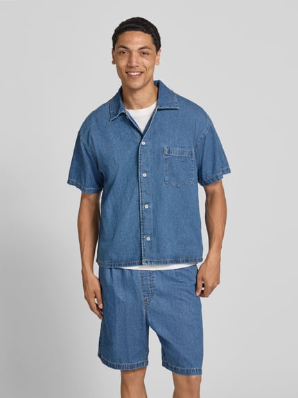 Männermodel trägt Modern Fit jeanshemd met borstzak model 'AUSTIN' van Jack & Jones, pure gewaxte katoen, kentkraag, knoopsluiting, ruglengte 66 cm, schouderbreedte 55 cm, mouwlengte 22 cm, blauw, structuur zichtbaar, eenvoudige vormen, ganzekörperansicht van voren