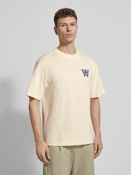 Männermodel trägt Relaxed Fit T-Shirt mit Logo-Print Modell 'Liam' von Wood Wood in Beige, Baumwolle, Rundhalsausschnitt, Ganzkörperansicht von vorne