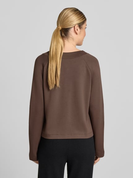 Frauenmodel trägt Regular Fit Sweatshirt mit V-Ausschnitt von SCHIESSER im elastischen Modal-Mix, Ziernähte, Ganzkörperansicht Rückansicht.