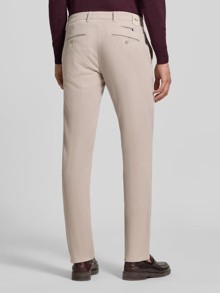 Männermodel trägt hellbeige Modern Fit Chino aus Baumwoll-Mix Modell 'Fabio' von Brax, Herren Schmale Hose, Ganzkörperansicht Rückansicht.