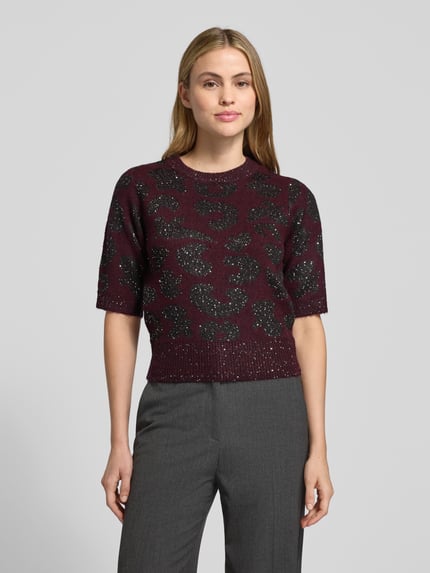Frauenmodel trägt Shaped Fit Strickpullover mit Woll-Anteil Modell 'ZUZU 2/4 O-NECK PULLOVER' von Vero Moda in Bordeaux mit schimmerndem abstraktem Muster, Pailletten und Rundhalsausschnitt, Nahaufnahme Oberkörper.