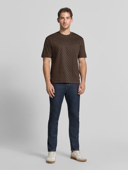Männermodel trägt Regular Fit T-Shirt aus reiner Baumwolle Modell 'Varo' von JOOP! COLLECTION, braun gemustert, Ganzkörperansicht von vorne.