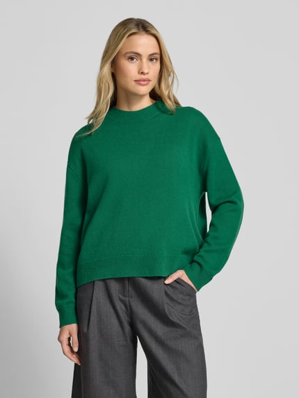 Vrouwenmodel draagt Oversized pullover uit puur kasjmier van Anine Bing in effen groen met opstaande kraag, tricotlook en ribboorden, ruglengte maat S 55 cm, voorkant volledige lichaamsopname.