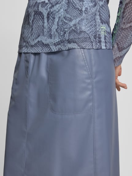 Frauenmodel trägt Midirock in Leder-Optik mit Eingrifftaschen von Marc Cain, straight Fit, elastischer Bund, Detailaufnahme Rückansicht.