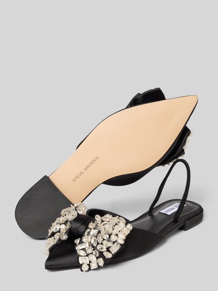 Produktfoto, Slipper mit Ziersteinbesatz Modell 'Sloane' von Steve Madden, spitze Passform, offene Ferse, Zierschleife, glatte Sohle, Absatzhöhe 2 cm, schwarz-silberfarbene Details, klare Struktur und glänzende Oberflächen