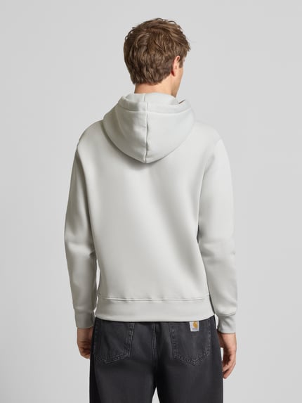Männermodel trägt Relaxed Fit Hoodie aus Baumwoll-Mix mit Label-Detail von Alpha Industries in Grau, Rückenansicht, Ganzkörperansicht Rückansicht. Baumwoll-Mix, Känguru-Tasche, Kapuze mit Tunnelzug, Rückenlänge 68 cm, Ärmellänge 74 cm.