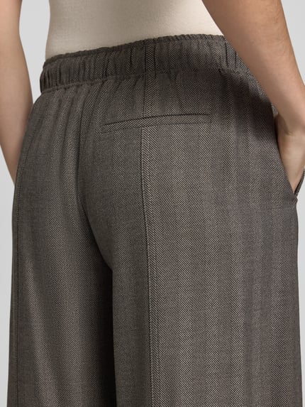 Frauenmodel trägt Regular Fit Hose mit Tunnelzugbund von OPUS, unifarbene Struktur in Fischgräten, Webware, Nahaufnahme Rückansicht.