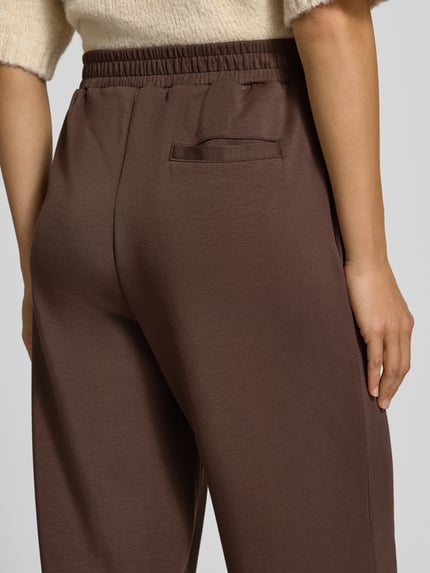 Frauenmodel trägt Pyjama-Hose mit Bundfalten Jersey von Marc O'Polo in unifarbener Optik, strukturierte Jersey-Verarbeitung, Nahaufnahme Rückansicht.